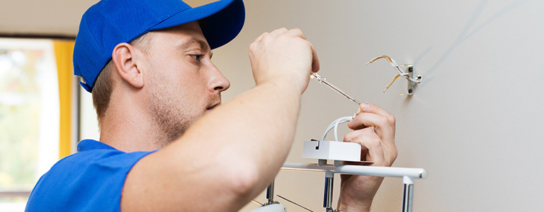 Image of man working on electrical wires coming out wall