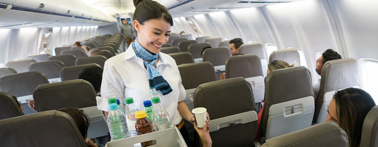 Flight attendant handing passenger a drink on commercial flight