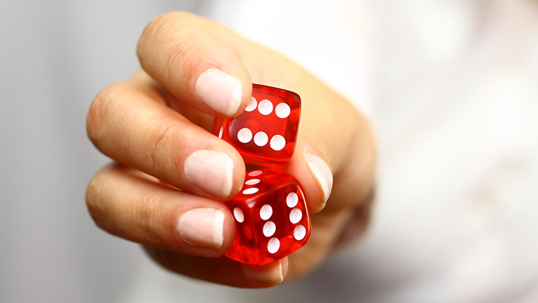 Female Hand holding a pair of red dice indicating randomized challenges