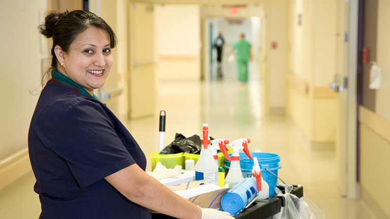 Female janitor smiling, depicting a public sector vs. private sector salary win in public sector