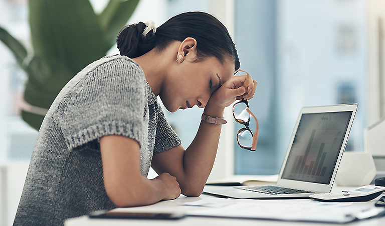 woman at desk holding head against hand, stressed out