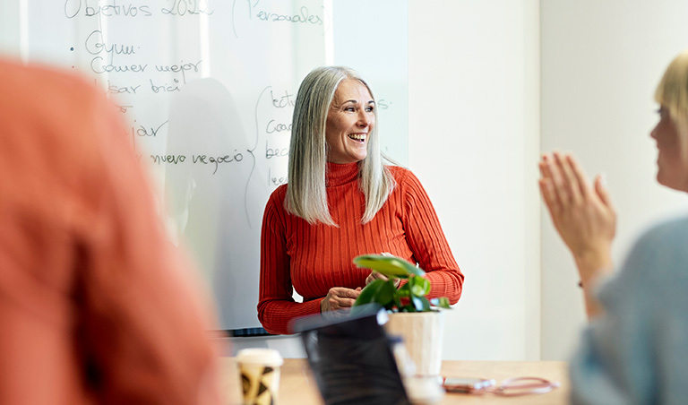 Woman standing in front of whiteboard, happy after midlife career change