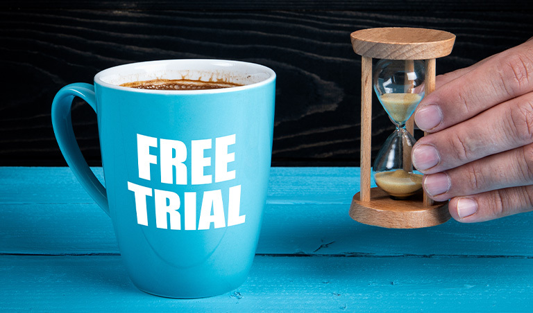 Blue Coffee Cup with "Free Trial" printed on it next to small hourglass suggesting free trial subscriptions