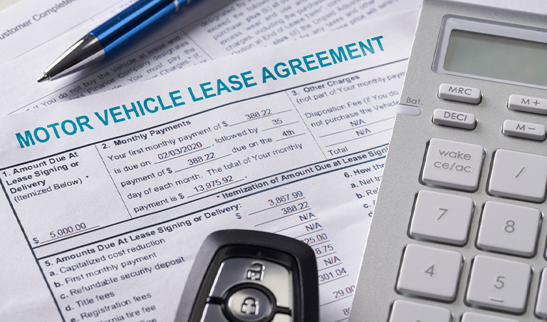 a car or vehicle lease agreement with a calculator, car key, and pen on top